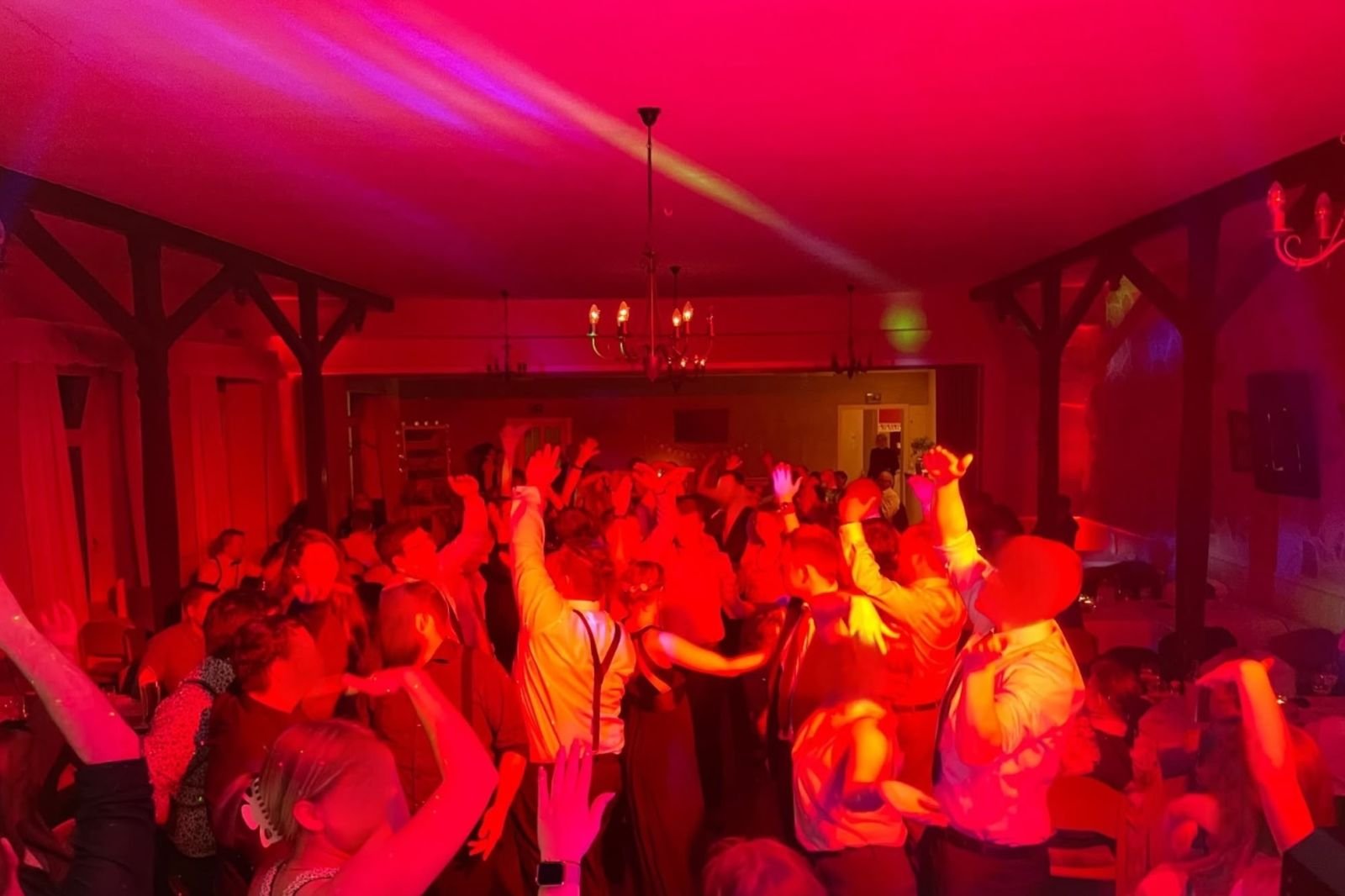 Volle Tanzfläche in rotem Licht bei einer Feier mit DJ Andreas Nause
